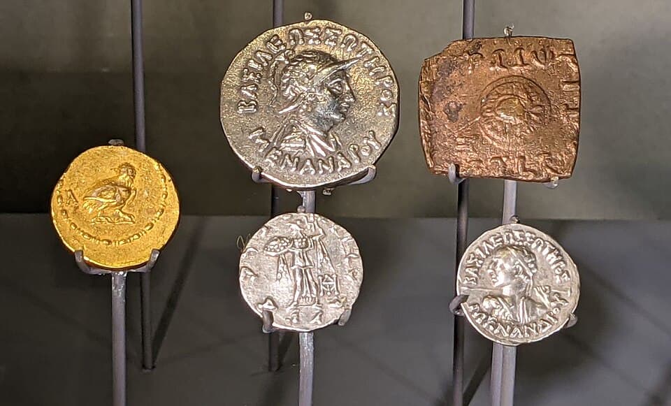 Coins of Menander: Indo Greek coins carry Greek on one side and Kharosthi or Brahmi on the other, a deliberate act of cultural accommodation.